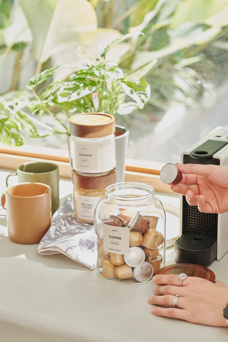A coffee corner with capsules in a labeled jar beside the machine.